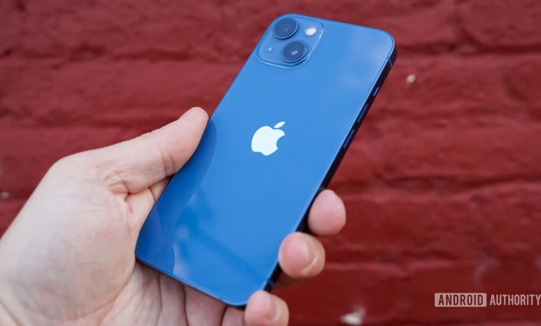 Apple iPhone 13 right rear profile in hand against brick wall