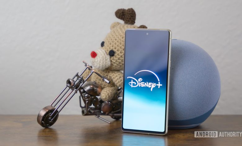 Disney Plus logo on smartphone laying on side table stock photo (2)