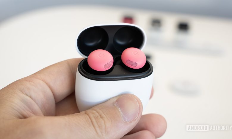 Google Pixel Buds Pro 2 in Peony color sitting in their charging case held in a man's left hand