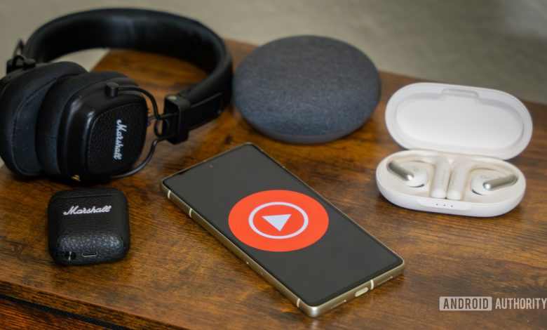 YouTube Music logo on smartphone, next to headphones and Nest Mini (1)