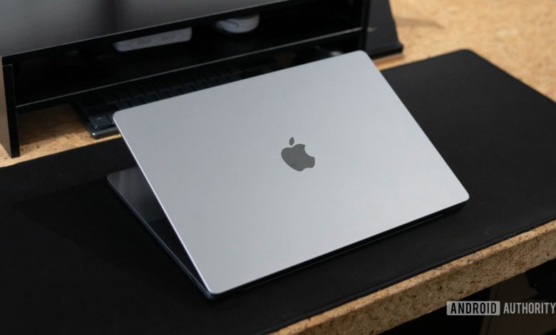 Apple MacBook Pro 2023 lid half open sitting on desk showing Apple logo