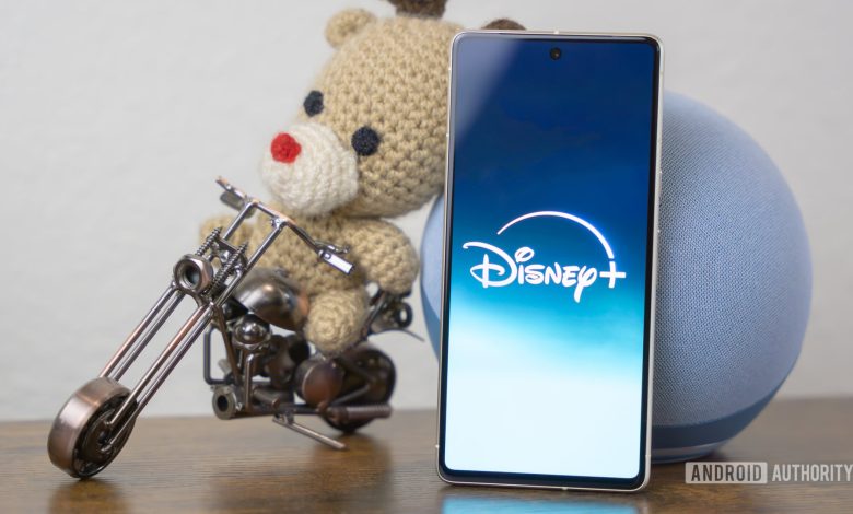 Disney Plus logo on smartphone laying on side table stock photo (3)