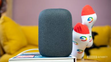 Google Nest Audio in gray on top of book in front of yellow couch.