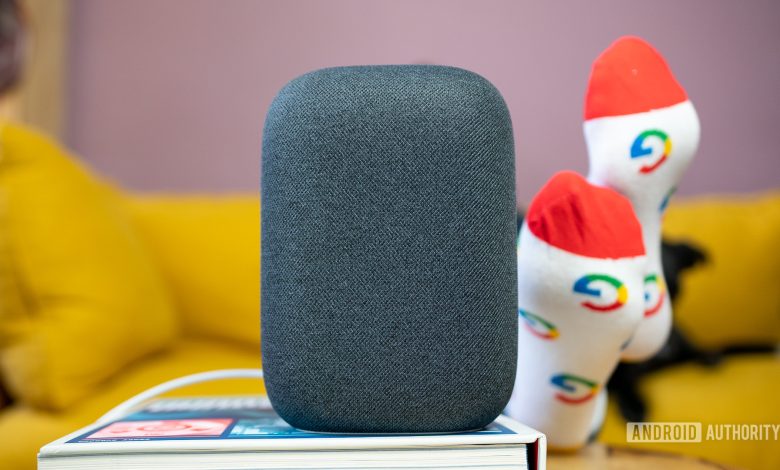 Google Nest Audio in gray on top of book in front of yellow couch.