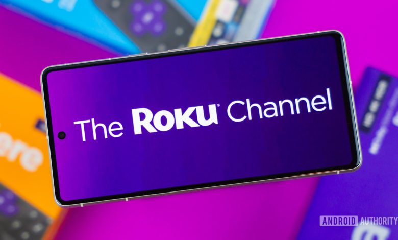 Stock photo of The Roku Channel logo on phone next to Roku boxes 2