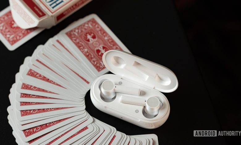 The OnePlus Buds Z cheap true wireless earbuds in white rest in the charging case which is surrounded by a pile of mini red playing cards.