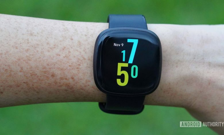 A Fitbit Versa 3 on a woman's wrist, displaying the Hawaiian Punch watch face.